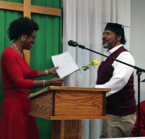 Ms. Williams awards a graduate with his certificate and a rose